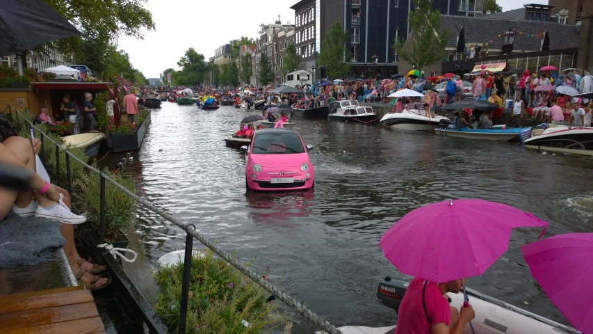 cars are traveling in the canal as people watch from the sidelines