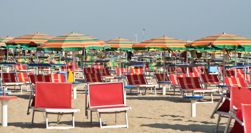 a large crowd of colorful umbrellas sitting on top of the beach