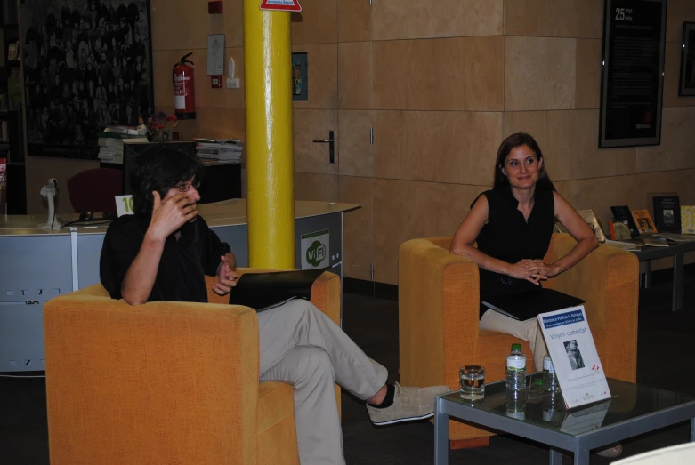 two people sitting on couches with one person talking on the phone