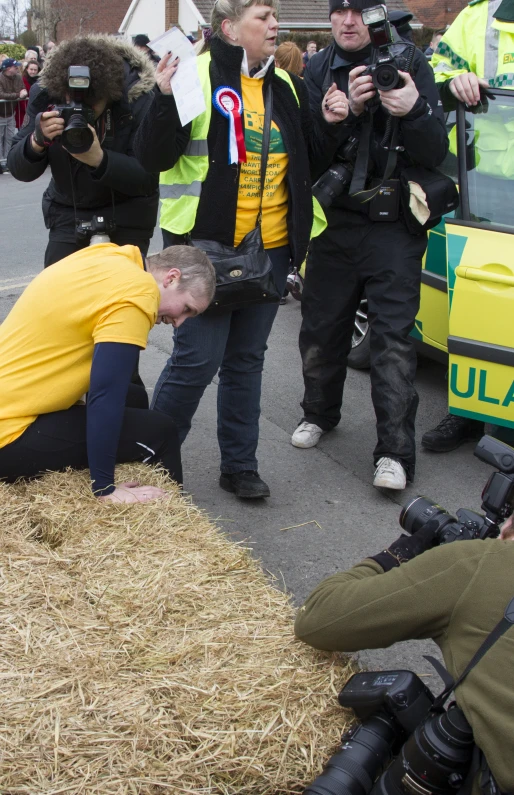 a man laying on a pile of hay holding a camera