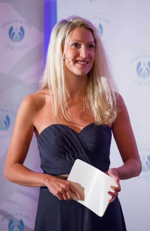 a blonde woman in a strapless dress holds a book