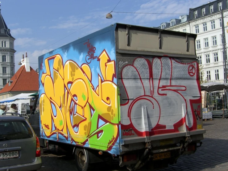 a box truck painted with various colors in a parking lot