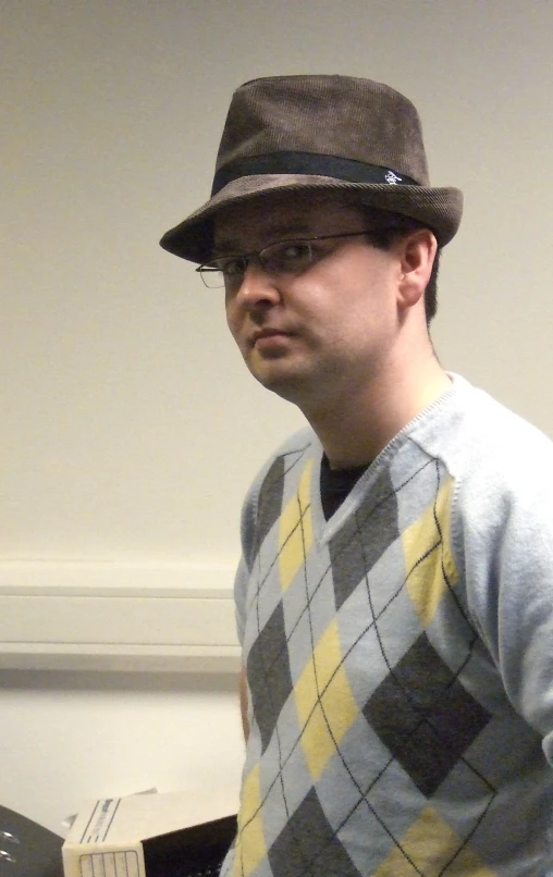 a man wearing a hat sitting by a desk