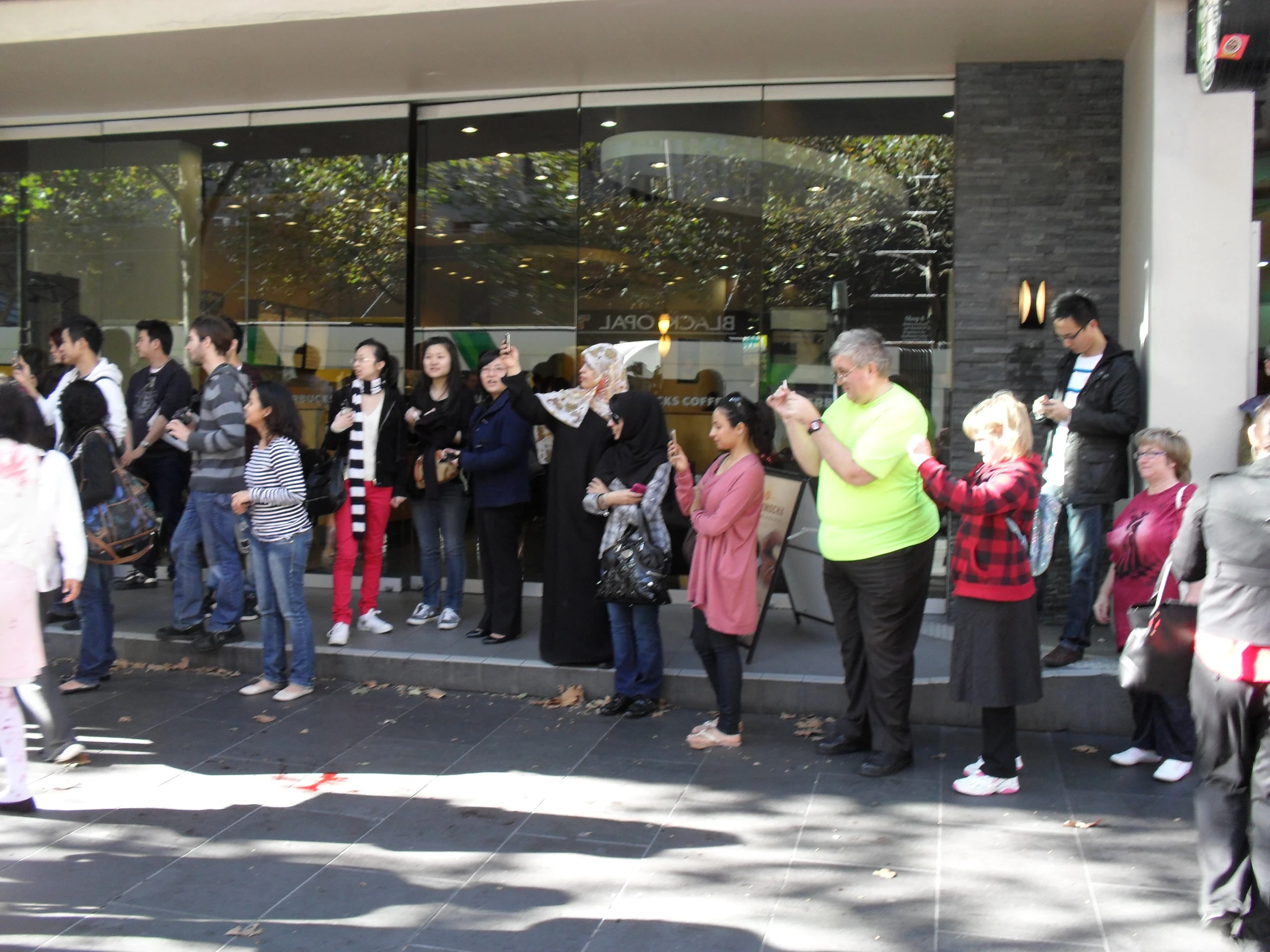 a crowd of people standing outside of a store window