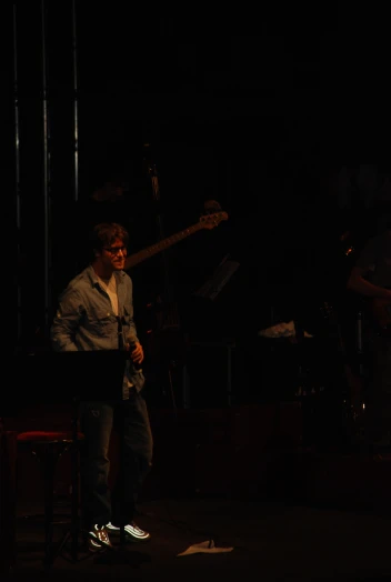 a band playing in the dark with one guy standing behind