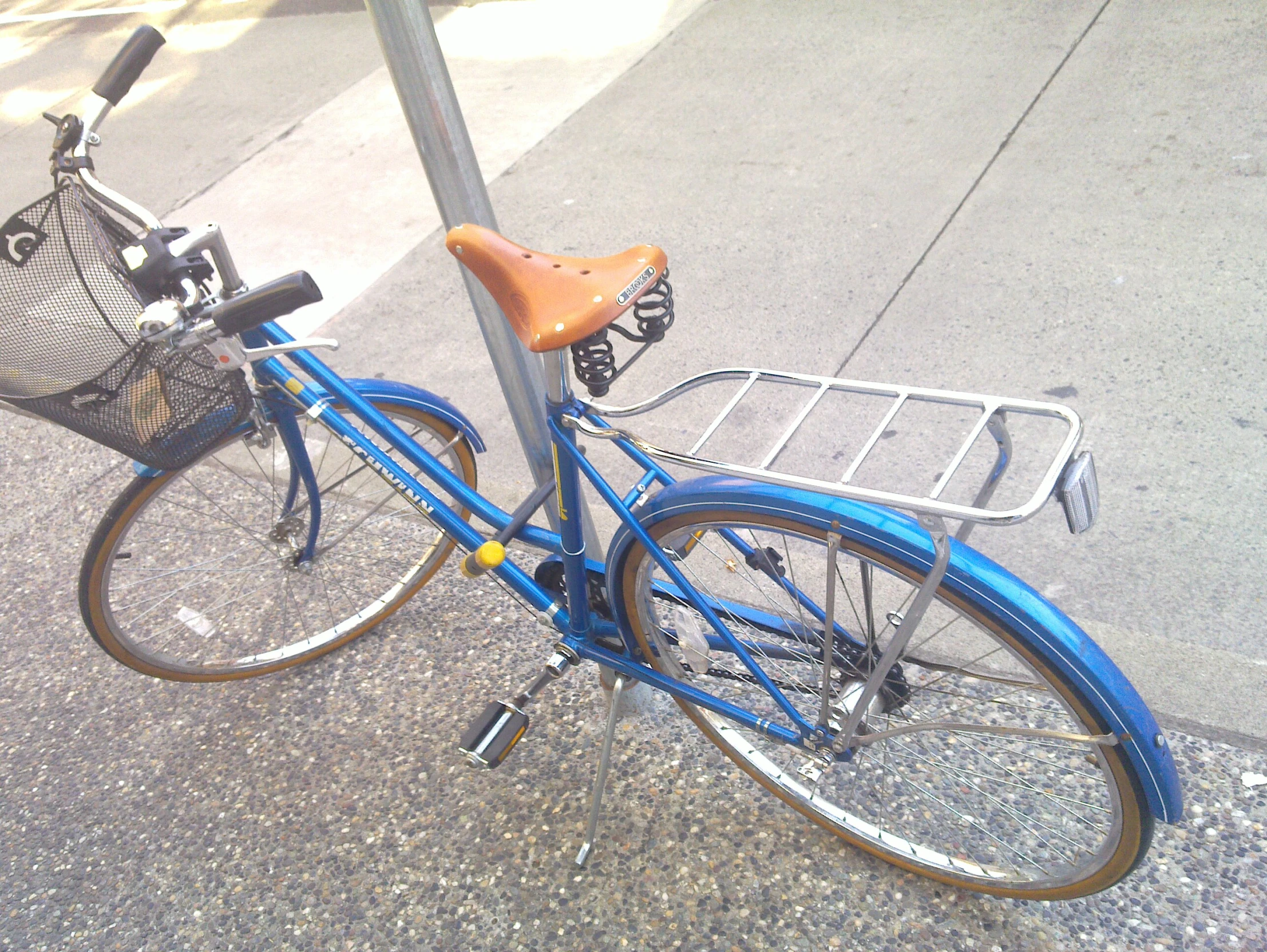 a blue bicycle is locked to a street pole