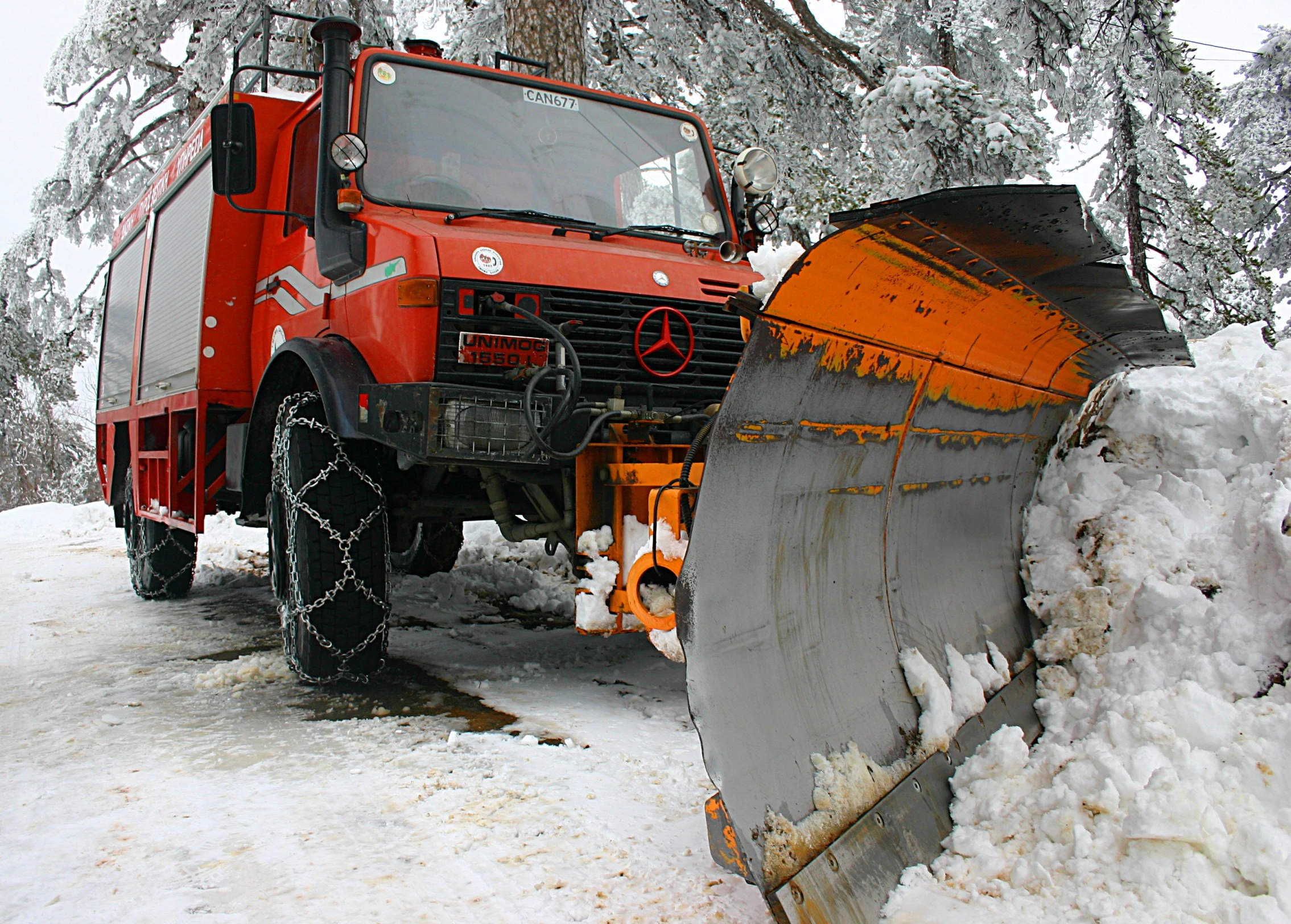 an orange truck parked next to a pile of snow