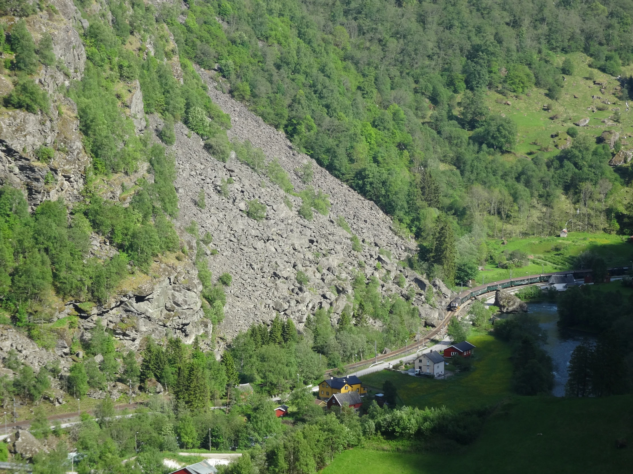 green hills and trees next to a body of water