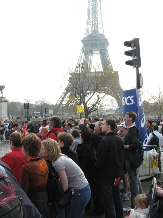 a crowd of people standing next to the eiffel tower