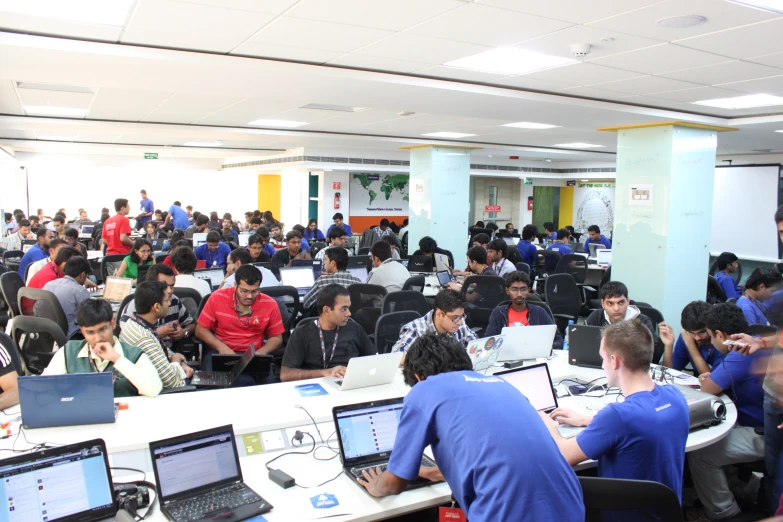 a large room filled with people working on laptops