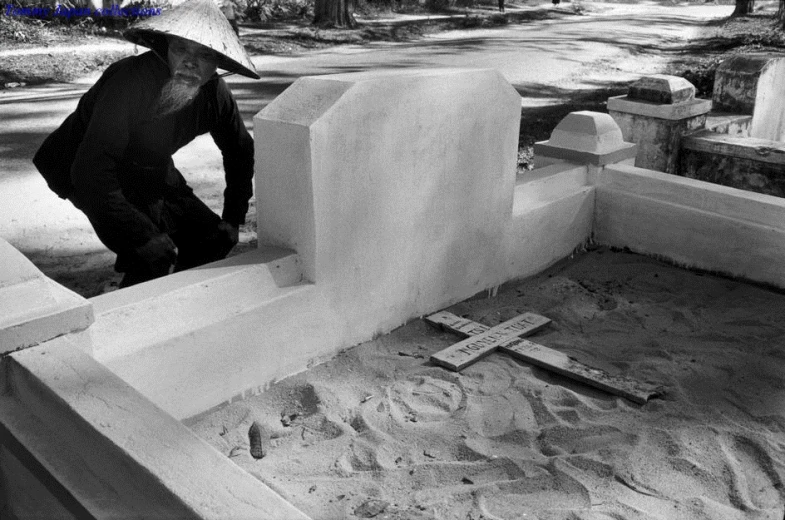 a man with a hat looking at a grave