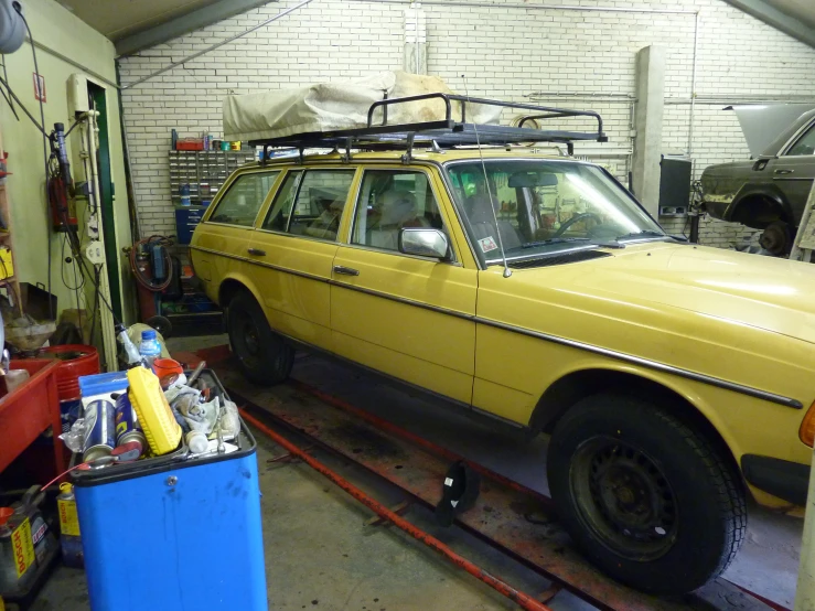 a yellow car parked in a garage with a yellow tow truck