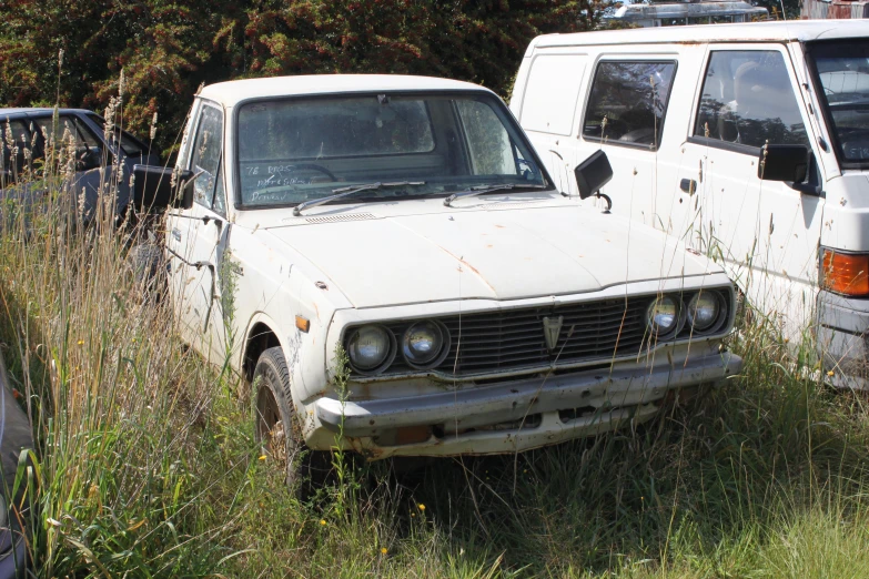 two abandoned vehicles sitting side by side in a field