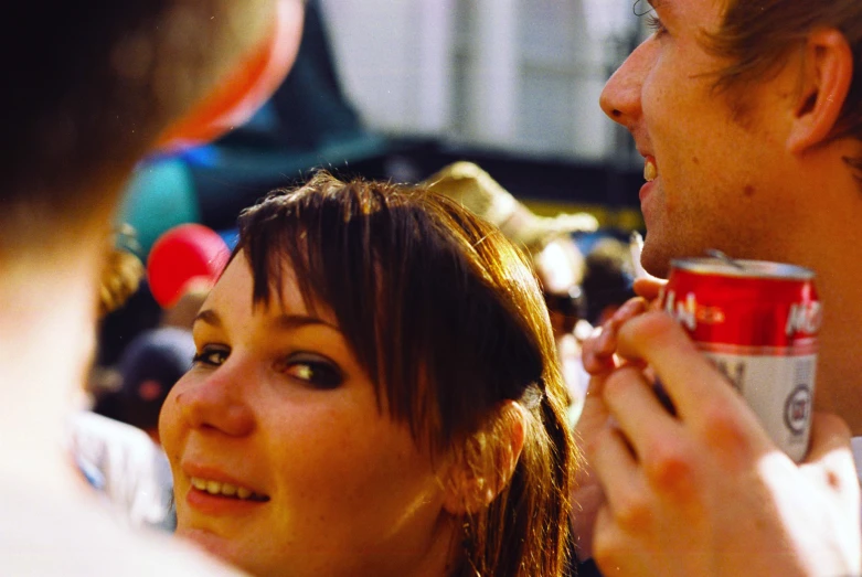 two people holding and eating soda cans at a party