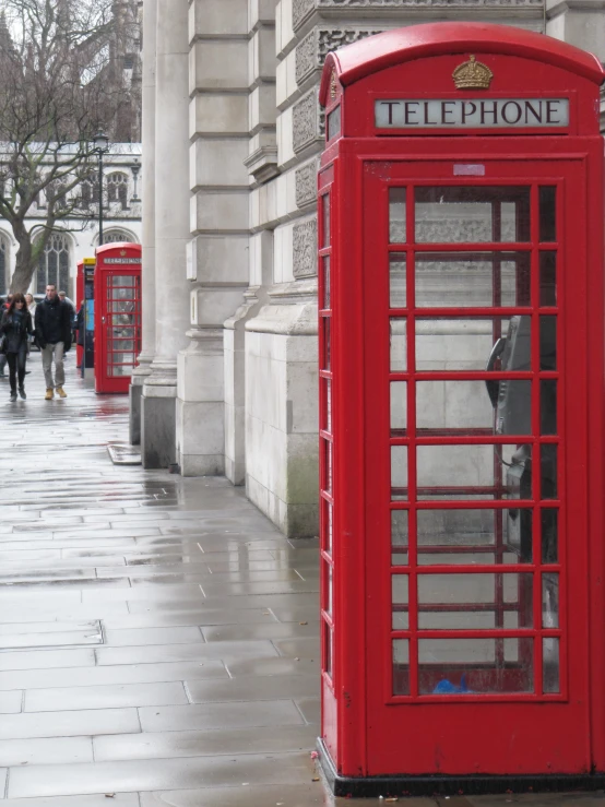 red british telephone booth near stone wall on sidewalk