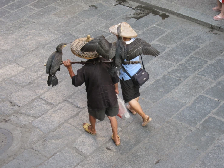 two people with hats and carrying a dead bird