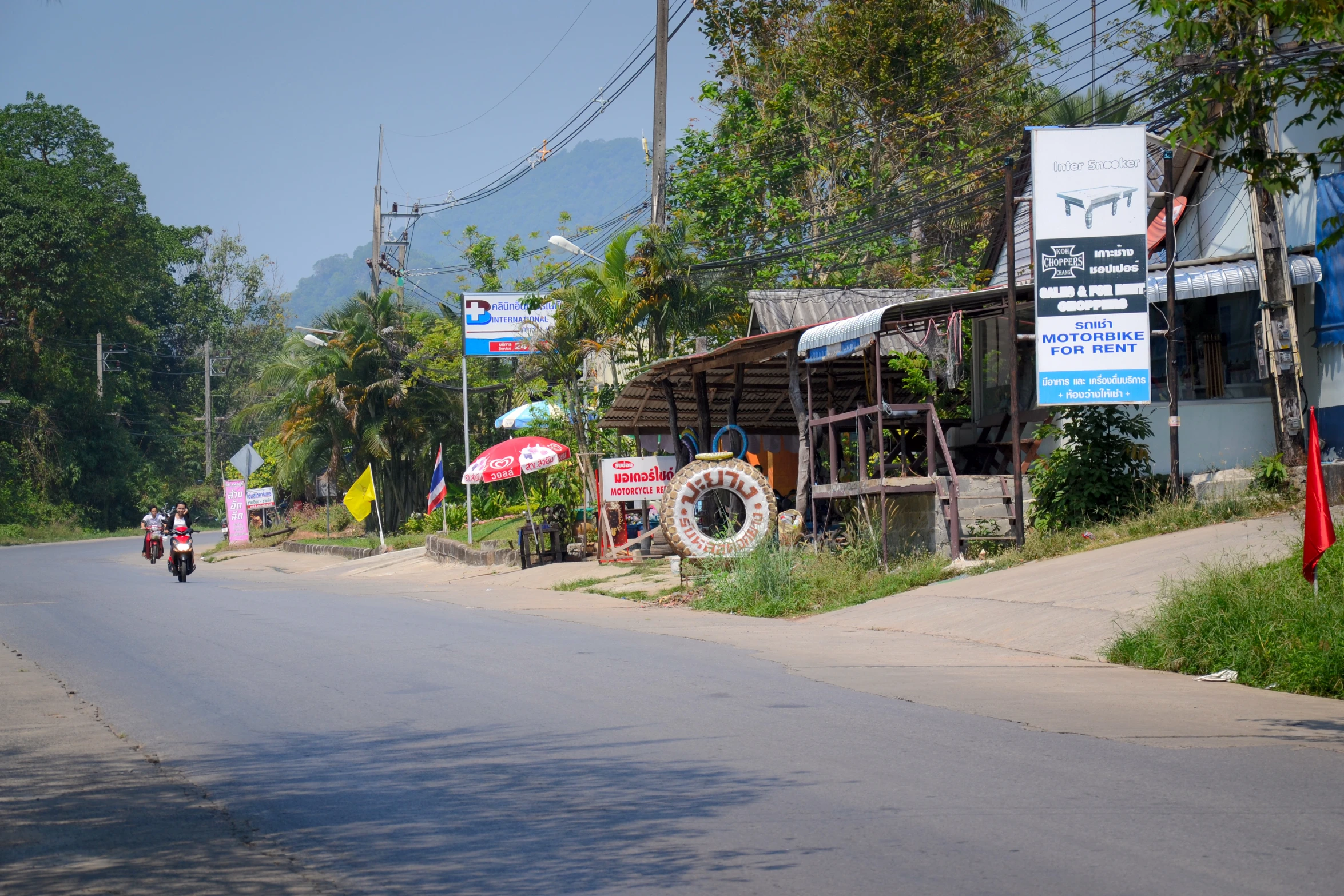 a motorcyclist rides down a street lined with small shops