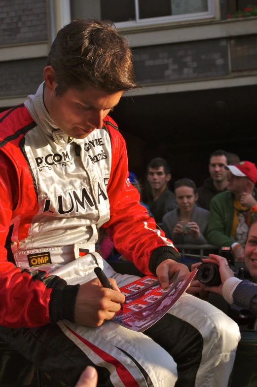 a man sitting and writing in his red jacket