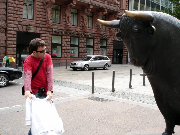 a man standing next to a cow statue on a sidewalk