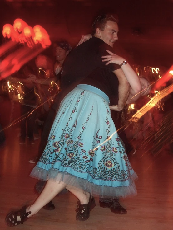 a woman and a man dancing with red lights in the background