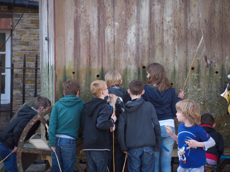 many children are standing outside and looking at soing