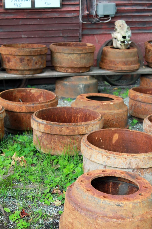 a lot of rusty rusted vases sitting in front of a red building