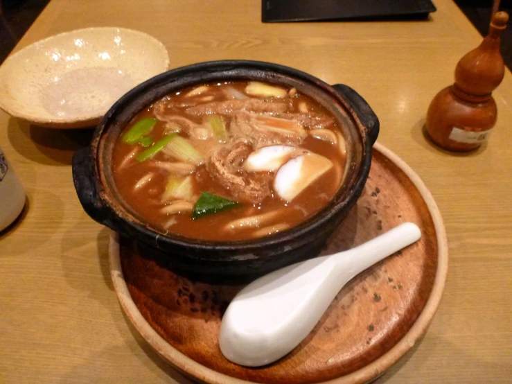a wooden bowl filled with a stew and spoon