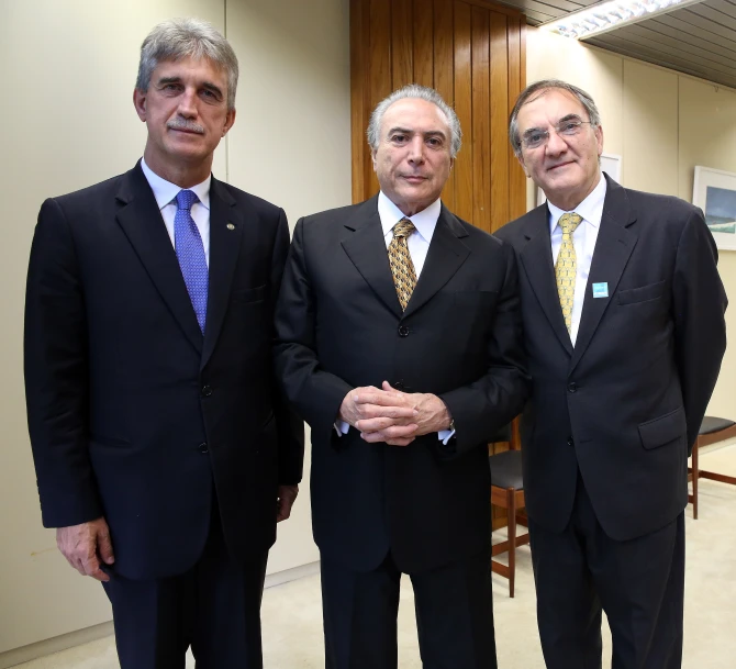 three men are in a room wearing ties and suits