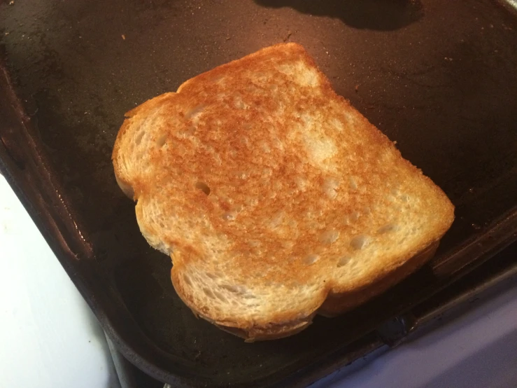 a piece of toast that is on a black baking sheet