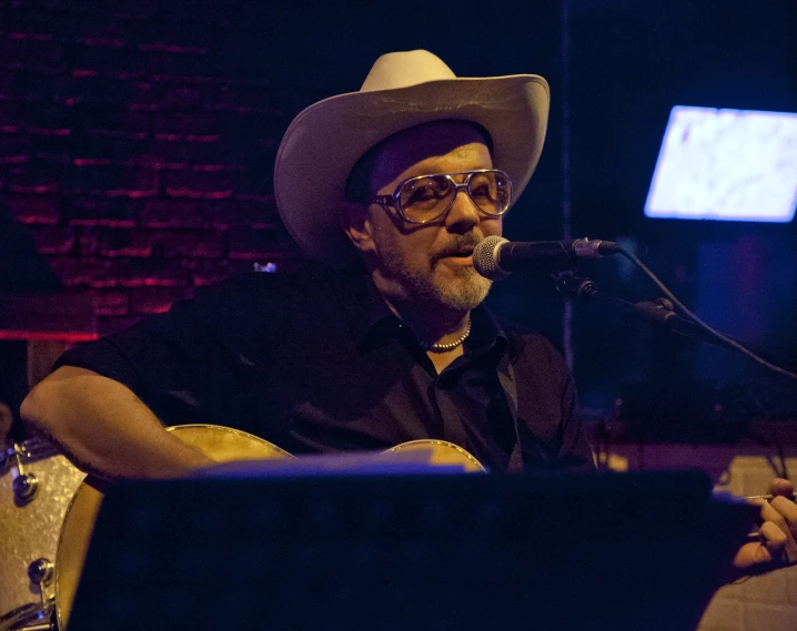 a man in cowboy attire sings into a microphone