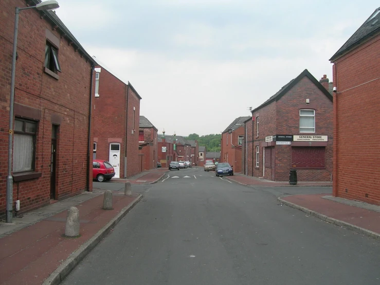 a street with cars parked between brick buildings
