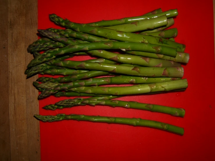 asparagus spears are arranged on a red surface
