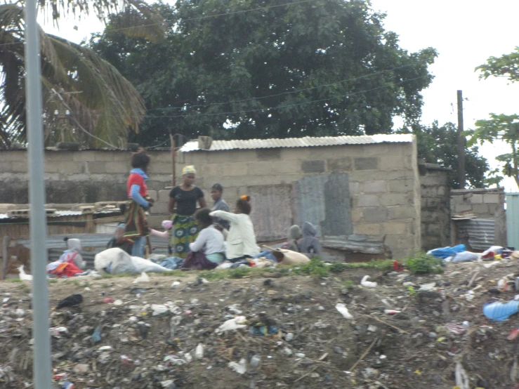 a group of people walking past a small building surrounded by trash
