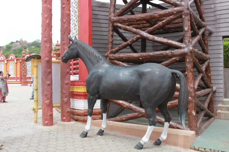 a statue of a horse in front of a wood structure