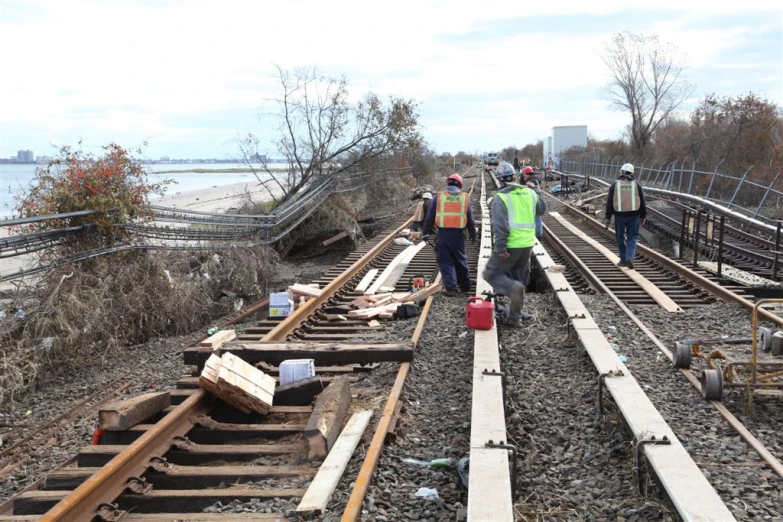 workers walking along a railroad track next to water