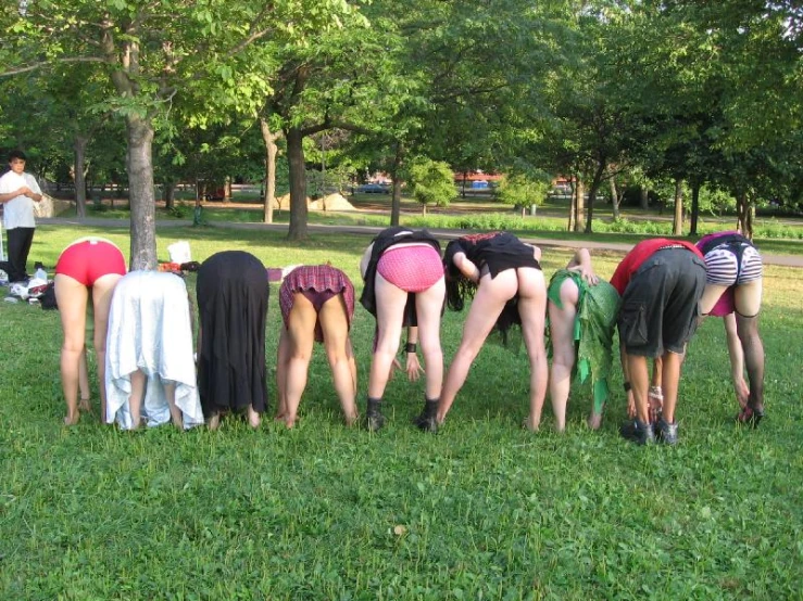 several people in short skirts bending over one another