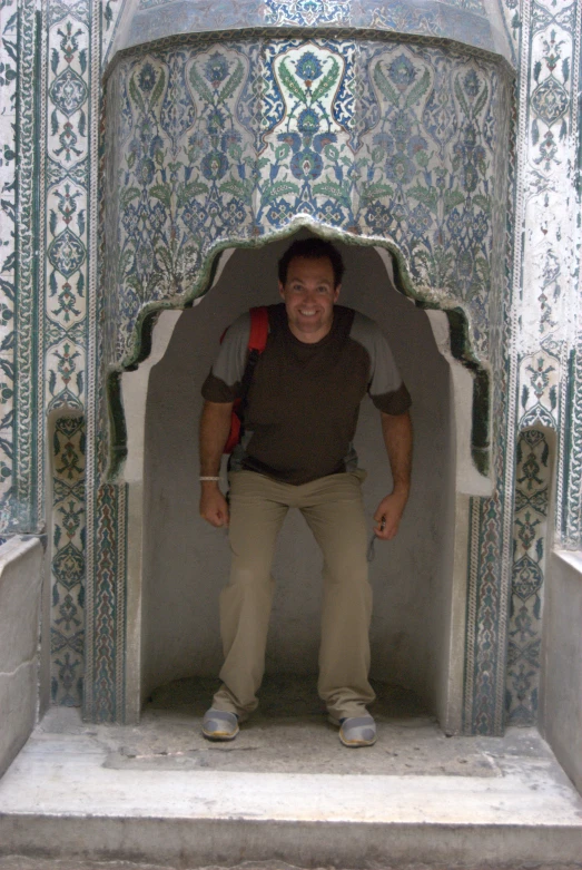 a man smiles while standing in a room with ornate stucco and stone work