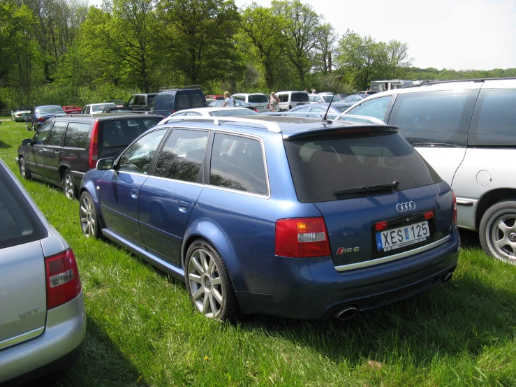 several cars are parked in a grassy lot