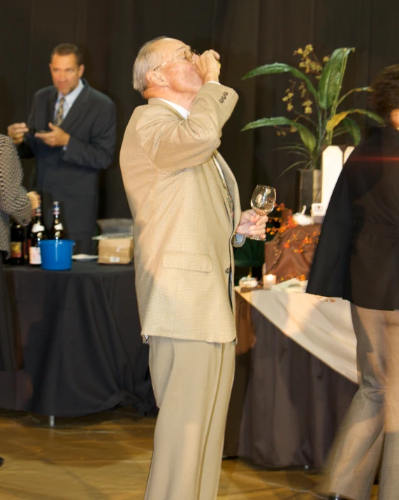 a man standing on a stage holding a wine glass