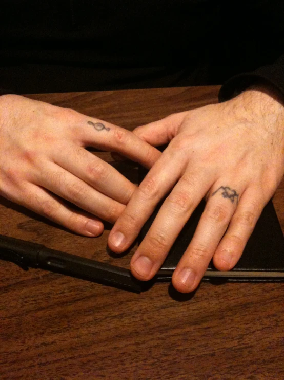 a close - up of two hands, with one with tattoos on it