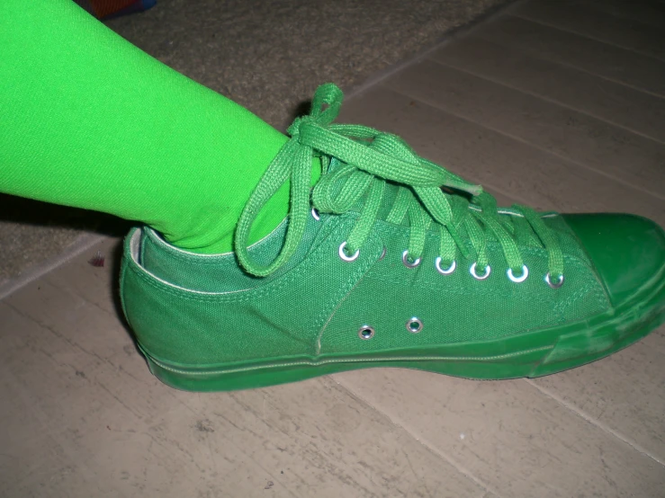 a persons shoe with green shoes that are not wearing