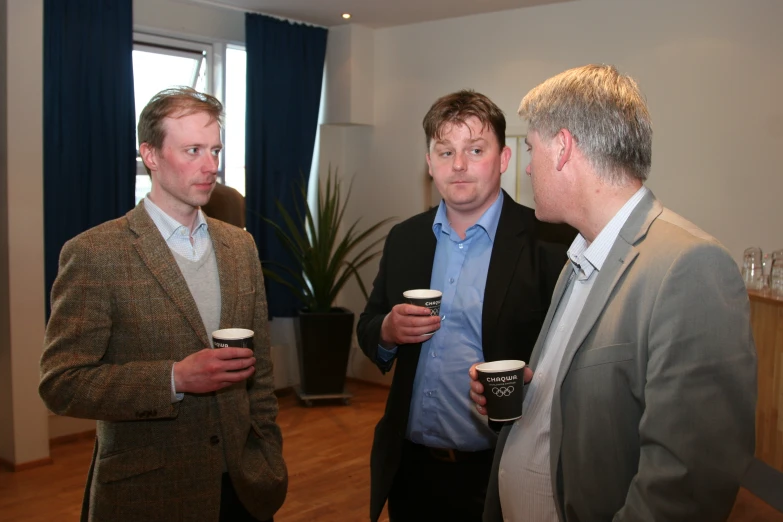 three men drinking coffee and having a conversation