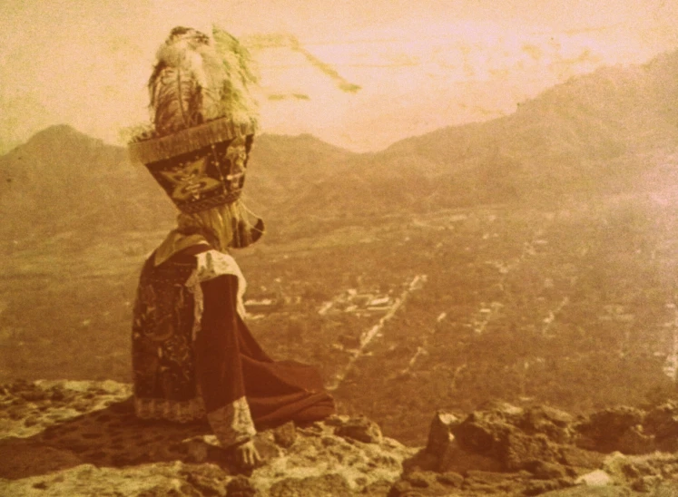 a woman with a large umbrella standing on top of a hill