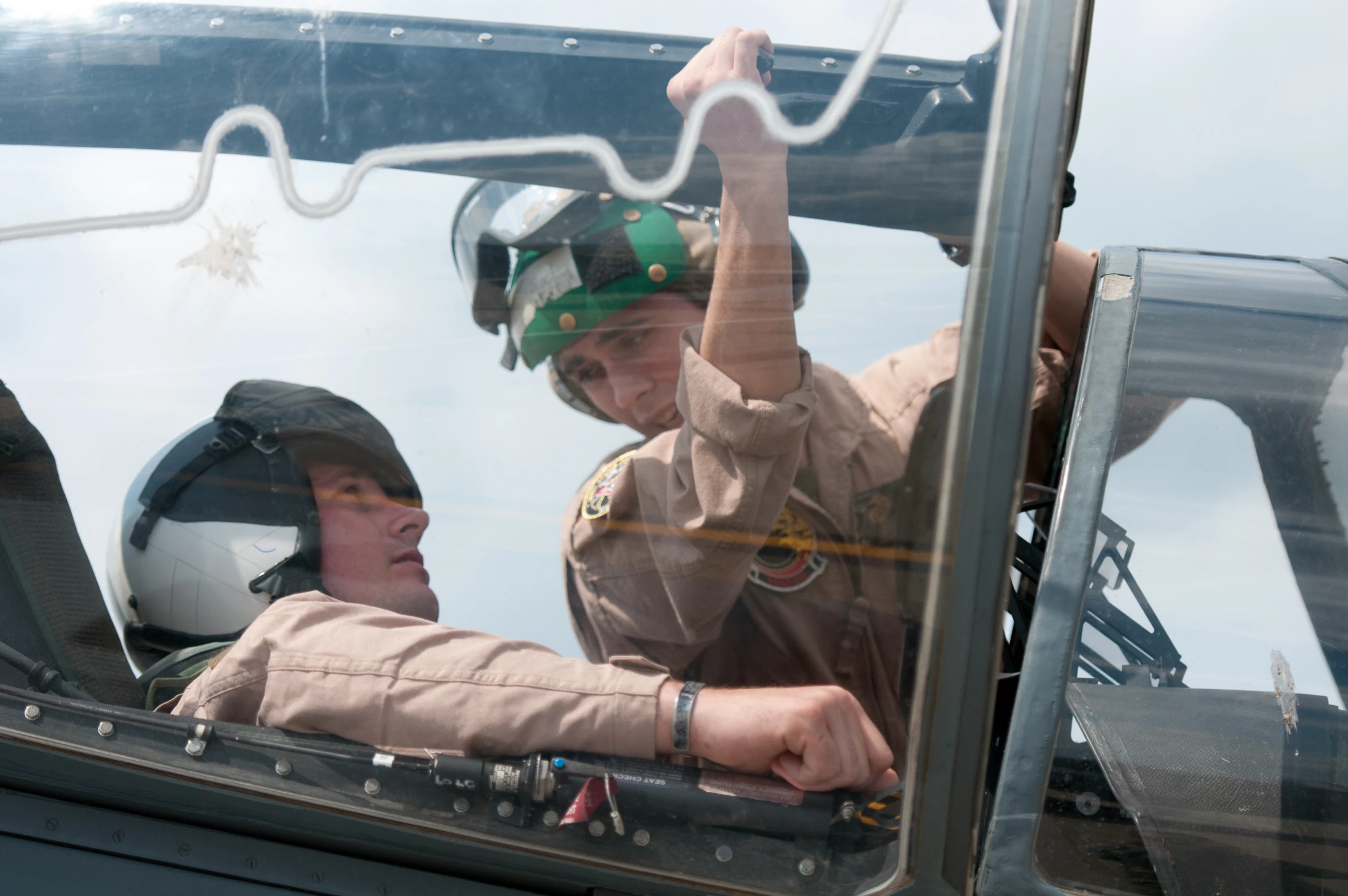 two people sitting in a military helicopter in the cockpit