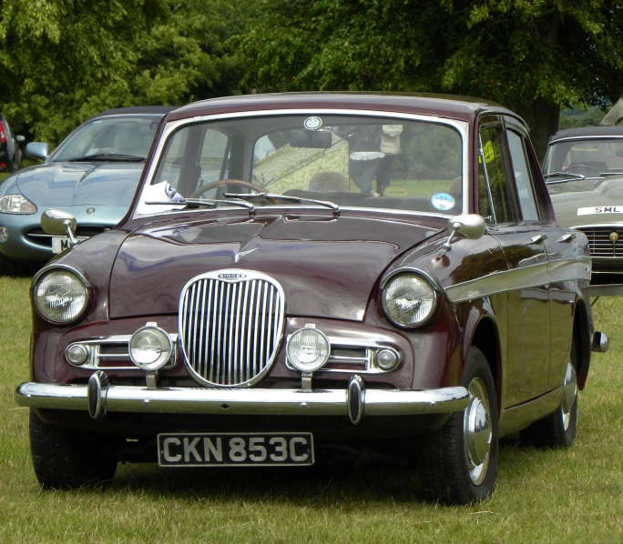 a brown vintage car parked in a grassy area