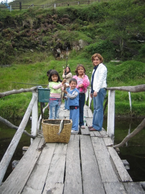 people standing on a bridge, a boy is holding a small fishing pole