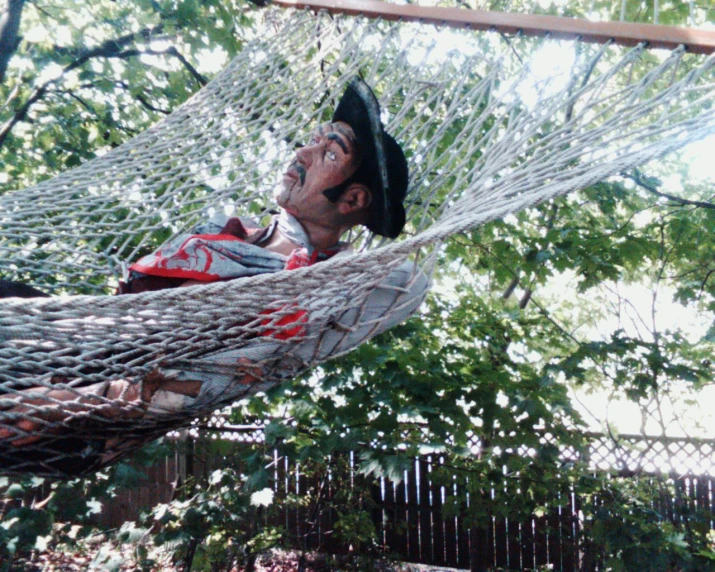 a man in a hat sitting in a hammock