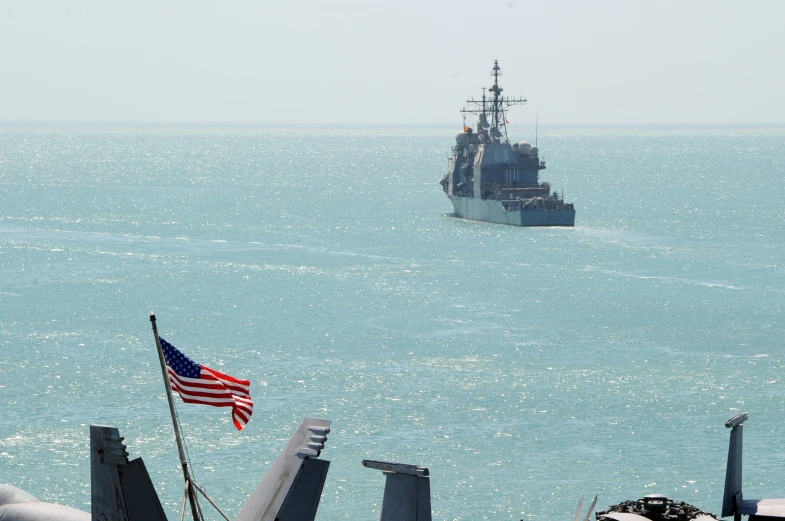 a large ship near the shore with a flag on it