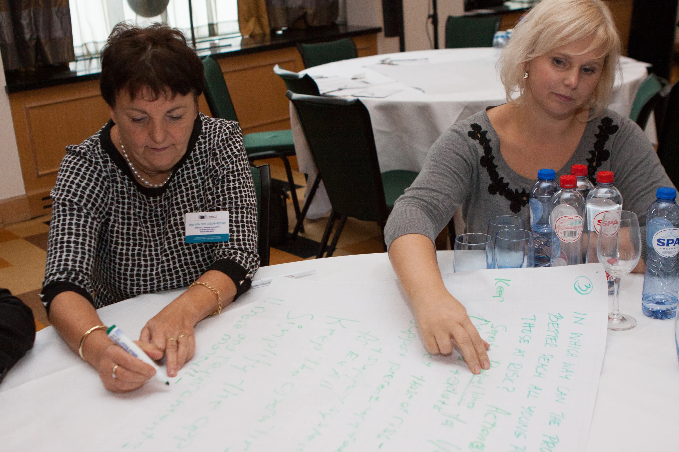 two women at a table writing on paper