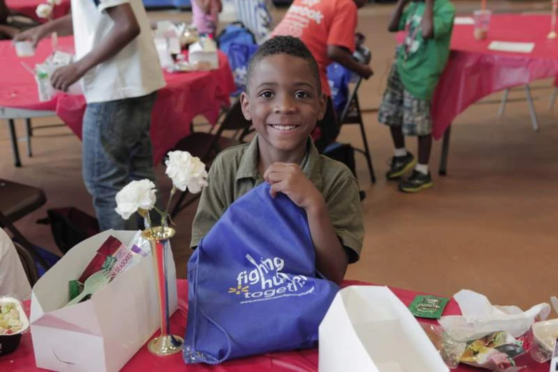 a child holds a bag and smiles at the camera